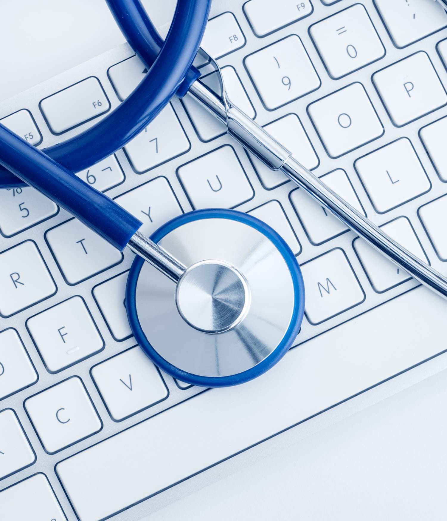 A blue stethoscope rests on a white computer keyboard, symbolizing the connection between healthcare and technology at the experience layer.