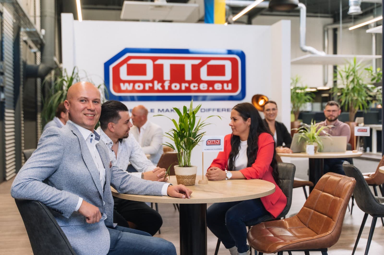 A group of professionals discusses the KWB Clee Energy Management App while sitting at a table in an office with the OTTO Work Force logo on the wall in the background.